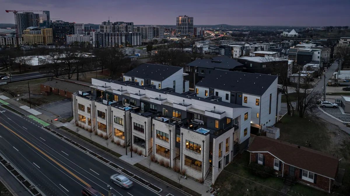 A lively street scene featuring modern townhouses, the city skyline in the background, and a welcoming street view. The image conveys walkability and proximity to restaurants, parks, and cultural hotspots, inviting guests to explore what's just minutes away from the property.