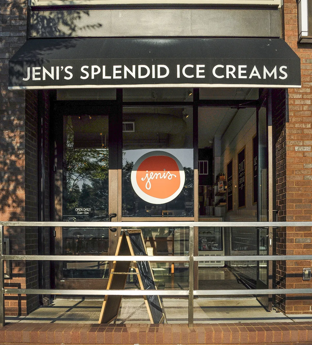 The storefront of Jeni’s Splendid Ice Creams, with bright signage, a glass entrance, and visitors enjoying themselves outside. The mood is cheerful and welcoming, perfect for families and children looking for a sweet treat after a day of exploring.