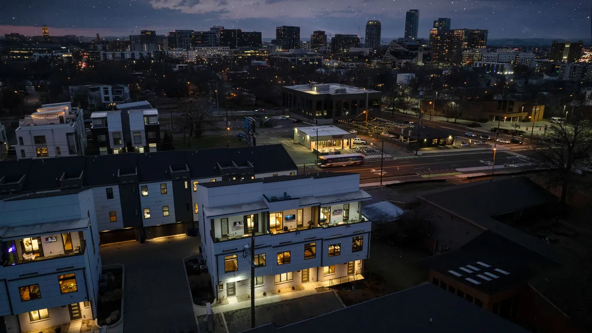 A modern building exterior with illuminated windows and a striking city skyline in the background. The balconies are set up for gatherings, and the city lights create a vibrant, celebratory mood—a perfect backdrop for rooftop soirées and evening get-togethers.